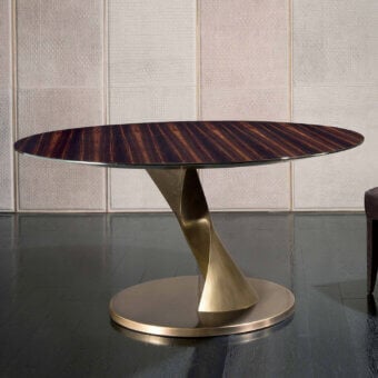 Zoe dining table, macassar ebony veneer, oval tabletop with sculptural brushed brass pedestal base on dark wood floor.