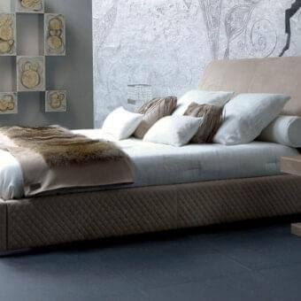 Sophisticated Rugiano Chloe bed with light brown textile, curved headboard and base exhibiting matelassé embroidery for restful relaxation