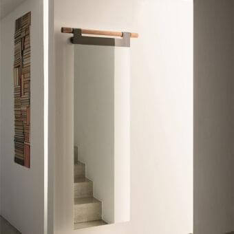 Distinguished Porada Hook mirror with clear glass suspended from solid canaletto walnut and dark chrome metal bracket