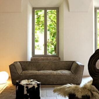 Low olive form below rectangular opening displaying green foliage framed by a light architectural surround and pale vertical surface