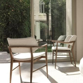 Graceful Porada Nissa chair with curved armrests and angled backrest in light fabric upholstery and canaletto walnut