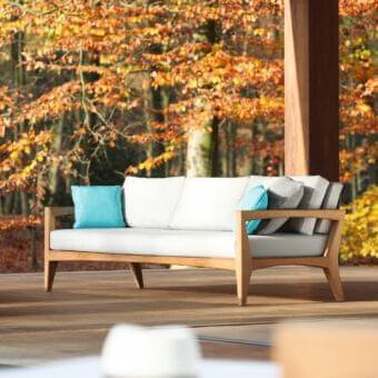Distinguished Royal Botania Zenhit sofa with light-toned teak wood structure and crisp white cushions accented in blue and gray