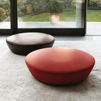 Reddish-orange and brownish-red rounded shapes sit on a textured surface before a window showing a green lawn and shrubs