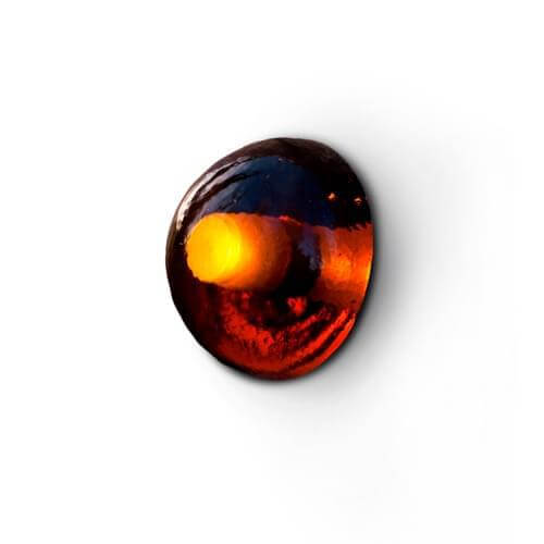 Dark oval reflective surface shows blurred warm-toned colors and gradients against a white backdrop