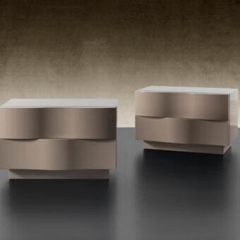 Two box forms with curved drawer fronts sit on a dark reflective surface against a gradient backdrop