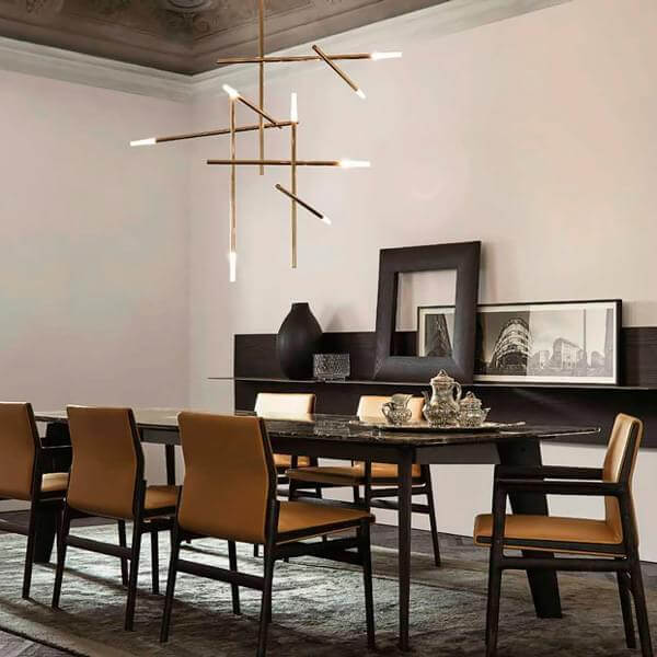 Dining room with dark wood console, marble table, tan leather chairs, brass chandelier, gray rug, and cityscape photograph.