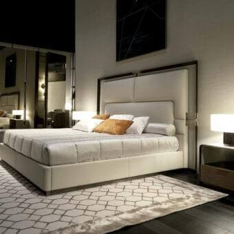 Distinguished Rugiano Grace bed with a low-profile upholstered headboard and refined bronze details in crisp white leather