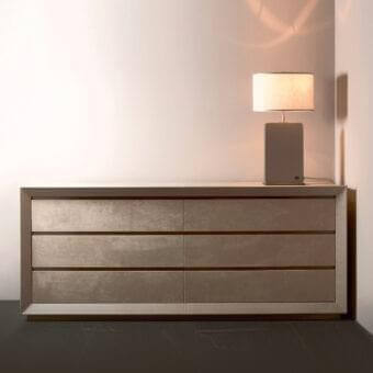 Six rectangular panels with mottled gold and bronze tones sit above a dark reflective surface with a cylindrical lamp