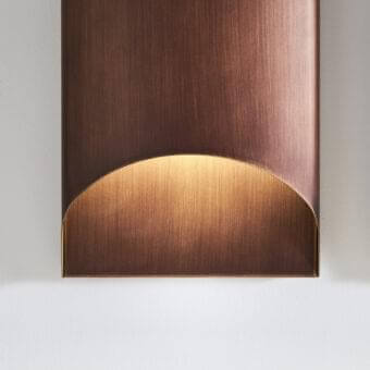 Sophisticated Penta Aprile wall lamp with curved metal structure and luxurious brushed bronze finish creating an inviting glow