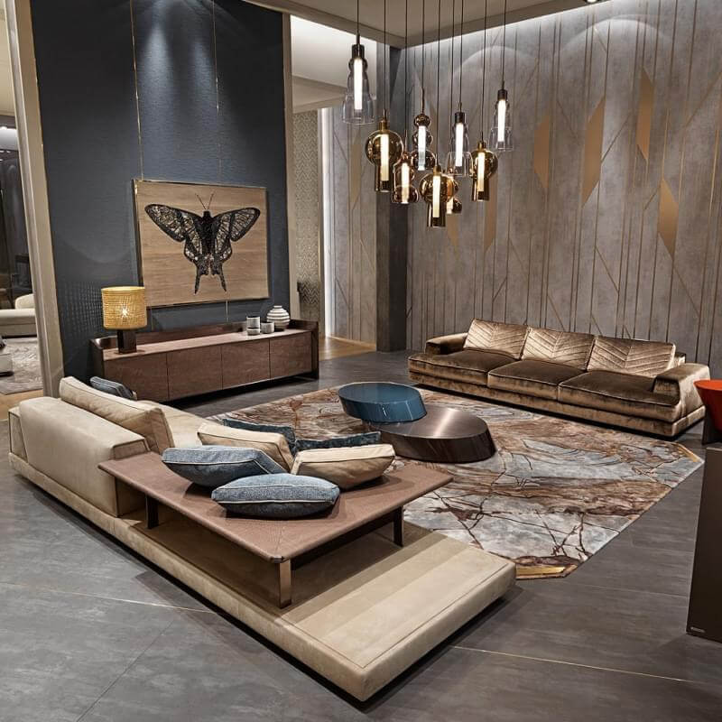Living room with beige & blue modular sofa, bronze velvet three-seater, wood console, gray tile floor, and amber glass chandelier.