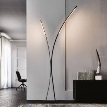 Curving dark structure rises beside a white architectural opening with fabric and a dark rug in the foreground