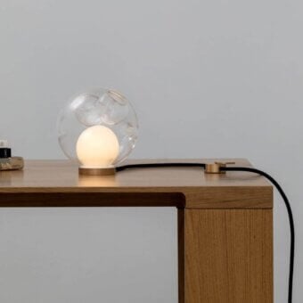 Superior Bocci 28 table lamp with a transparent blown glass shade and light-toned brass base with a black flexible cord