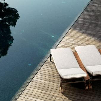 Innovative Talenti Casilda lounger with light gray textile cushions, a powder-coated stainless steel structure and innovative iroko wood shelf