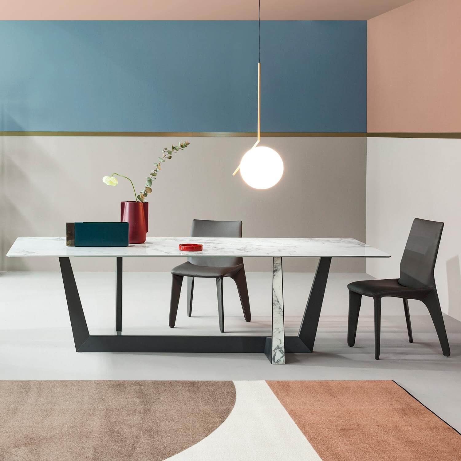 Marble dining table with dark gray angular base, rose & blue striped walls, spherical pendant light, terracotta & beige circular rug.