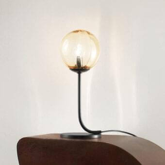 Superior Vistosi Puppet table lamp with curved form and warm amber blown glass lampshade featuring a delicate ‘dégradé’ finish and matte black metal base