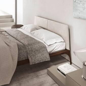 Elegant Presotto Relevè bed with light beige textile and dark brown wood veneer, showcasing dynamic lines