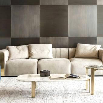 Exclusive Rugiano Luz sofa upholstered in light beige textile with uniquely curved armrests and refined brushed brass detailing
