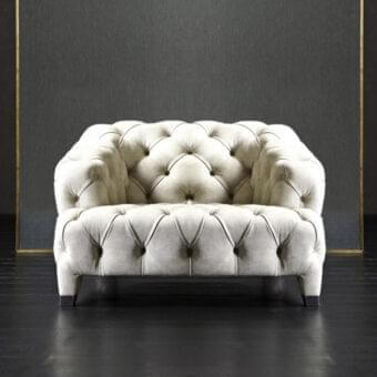 Light-colored button-tufted upholstery with curved arms rests on a dark reflective floor against a textured gray plane framed by metal borders