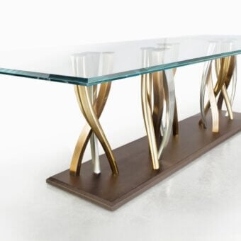 Exclusive Il Pezzo 8 table with clear glass top and sparkling intertwined metal supports in light bronze, champagne and nickel finishes
