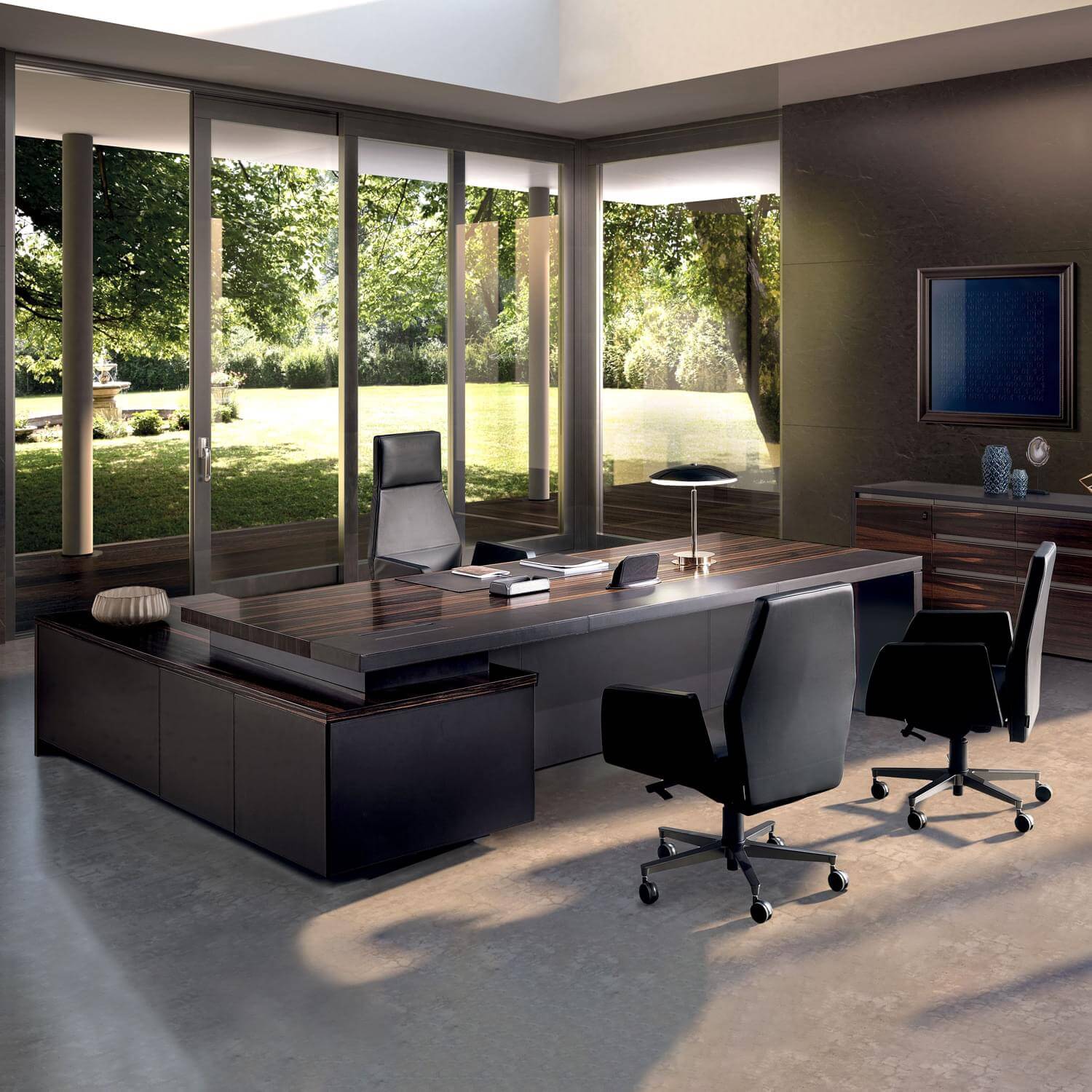 Executive desk with Makassar ebony veneer, black leather chairs, and chrome bases in a modern office with gray paneling and large windows.
