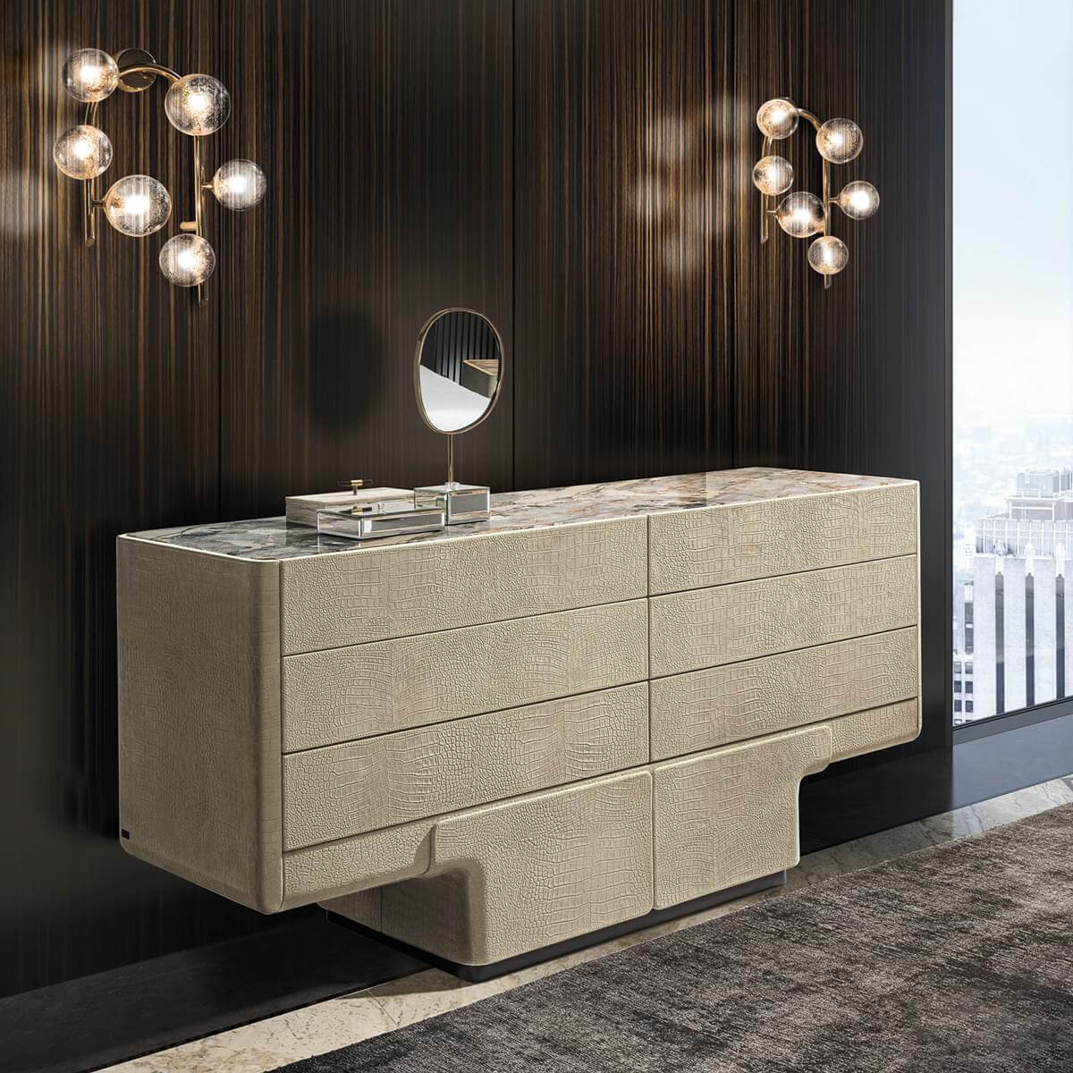 Console table, beige crocodile-texture upholstery, marble top with six drawers, flanked by brass and frosted glass sconces.