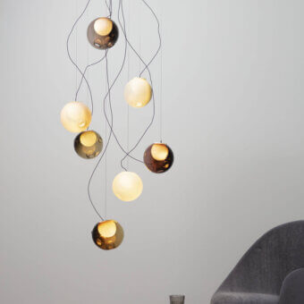Exceptional Bocci 28 lamp with nine clear glass spheres and milk white interiors suspended by black cables in amber, gold, and smoky gray tones