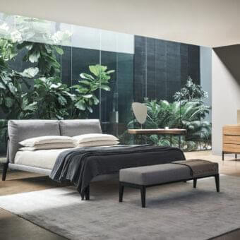 Exclusive Bonaldo Kriss bed with light grey textile headboard and frame built with dark-toned wooden legs