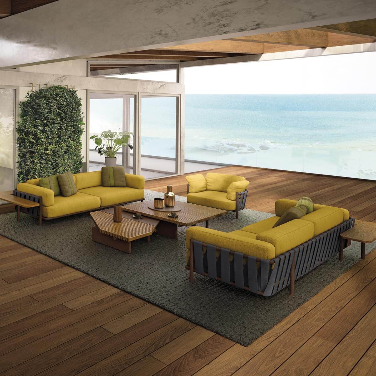 Modular sofas in mustard yellow fabric with olive pillows arranged on a gray rug in a hardwood-floored living room with ocean view.