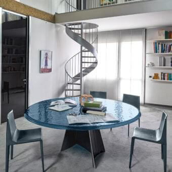 Captivating Arketipo Avalon table with rippling blue glass top and dynamically sculpted dark matte iron base