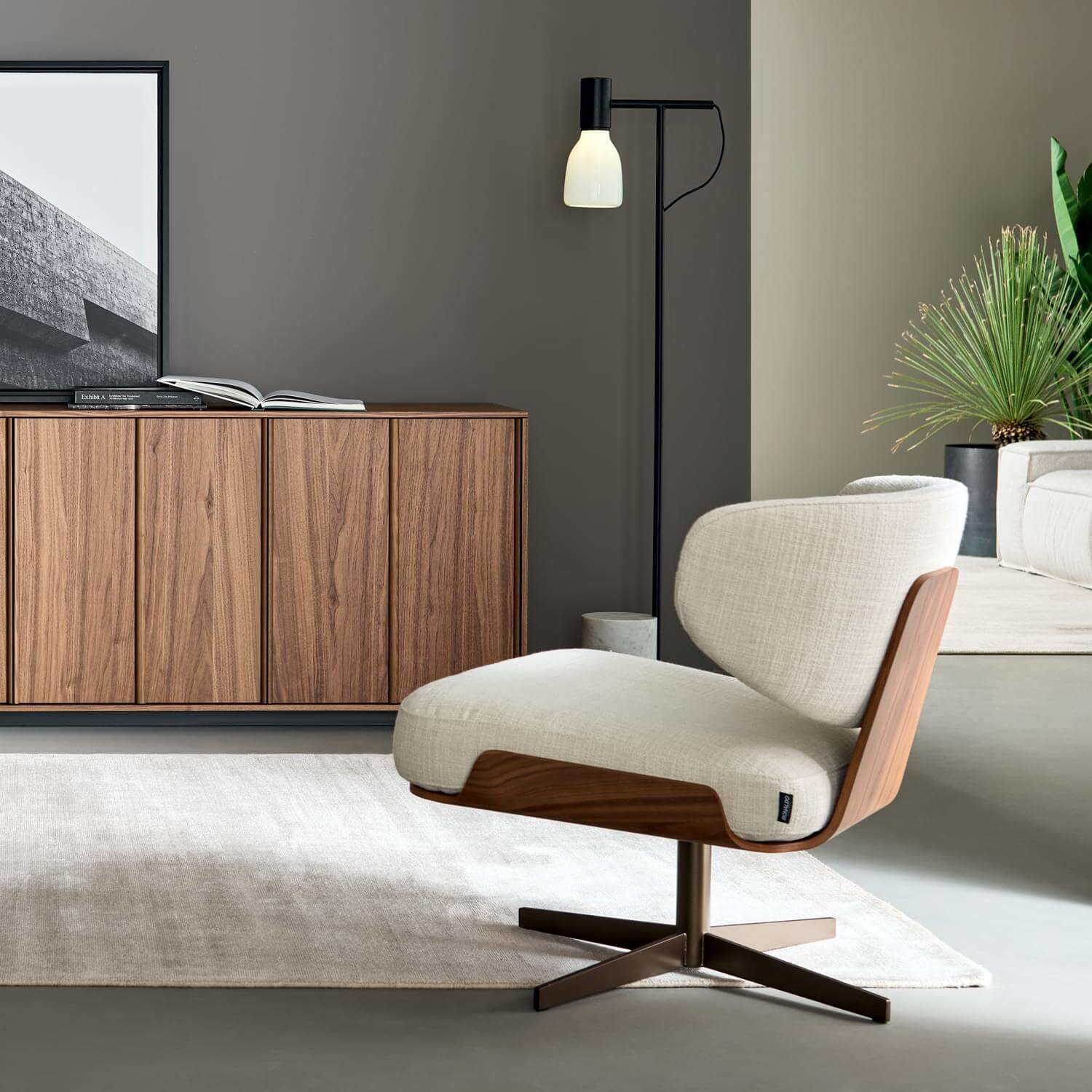 Swivel armchair with light beige fabric upholstery, walnut wood frame, and brushed bronze star base in a modern living room setting.