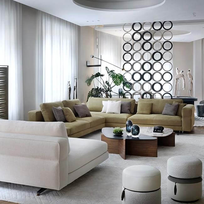 Giorgetti living room with olive-green L-shaped sofa, gray ottomans, dark wood coffee table, and circular metal wall rings.