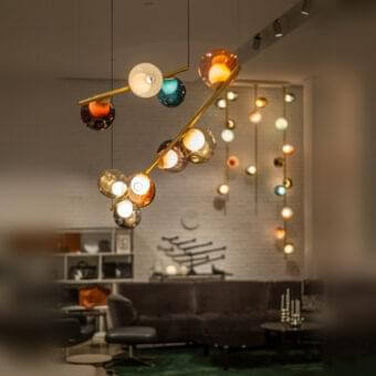 Captivating Bocci 28 Stem suspension lamp with hand-blown glass spheres in amber, orange, white, and teal, built with an unlacquered brass stem