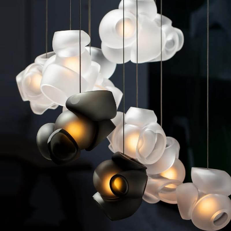 Bocci chandelier, white ceramic and dark bronze, asymmetrical arrangement of overlapping rounded and angular fixtures with diffused lighting.