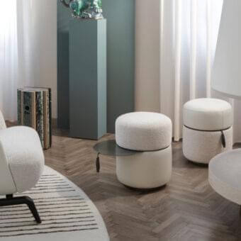 Exclusive Giorgetti Otto ottoman with creamy boucle-like fabric and dark gray swiveling steel, accented by a gray leather ribbon pull