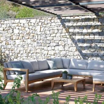 Sophisticated Royal Botania Zenhit sectional with teak wood frame and plush fabric seat cushions in light gray tones