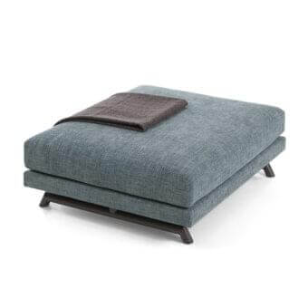 Rectangular padded shape with blue-grey fabric texture supports a smaller dark brown rectangular object on angled dark legs