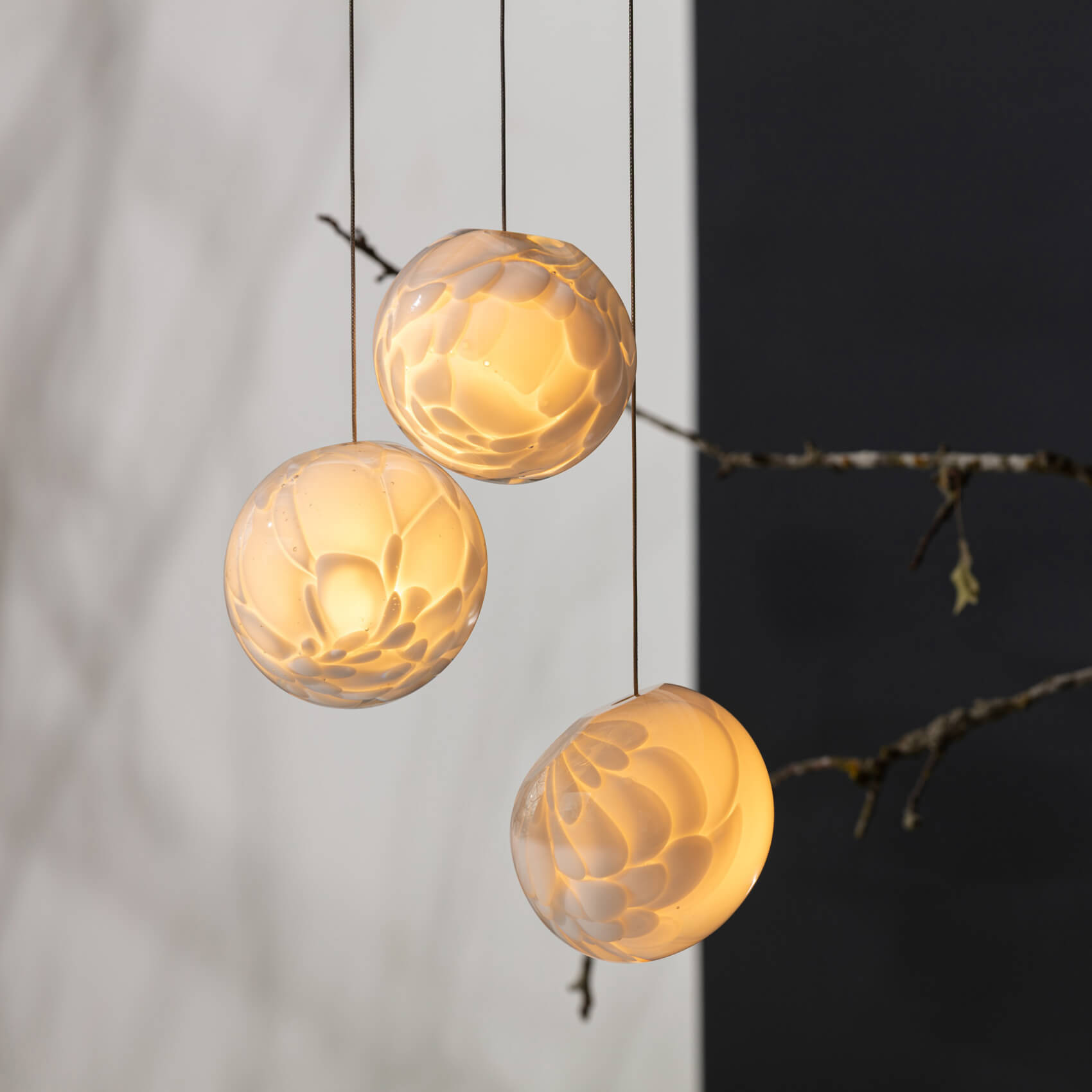 Bocci 118 suspension lamps, translucent glass, spherical shapes with textured petal-like surfaces hang against white and dark gray walls.