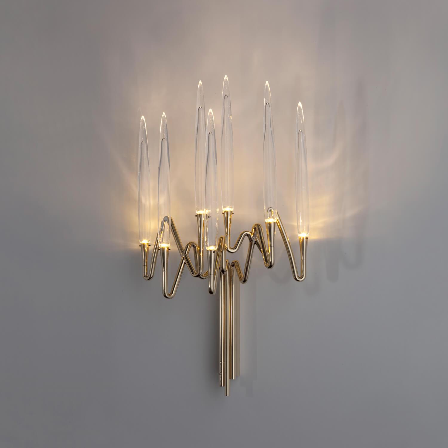 Il Pezzo Mancante wall lamp, polished brass with clear glass shades, featuring curved stem and organic, multi-rod structure.