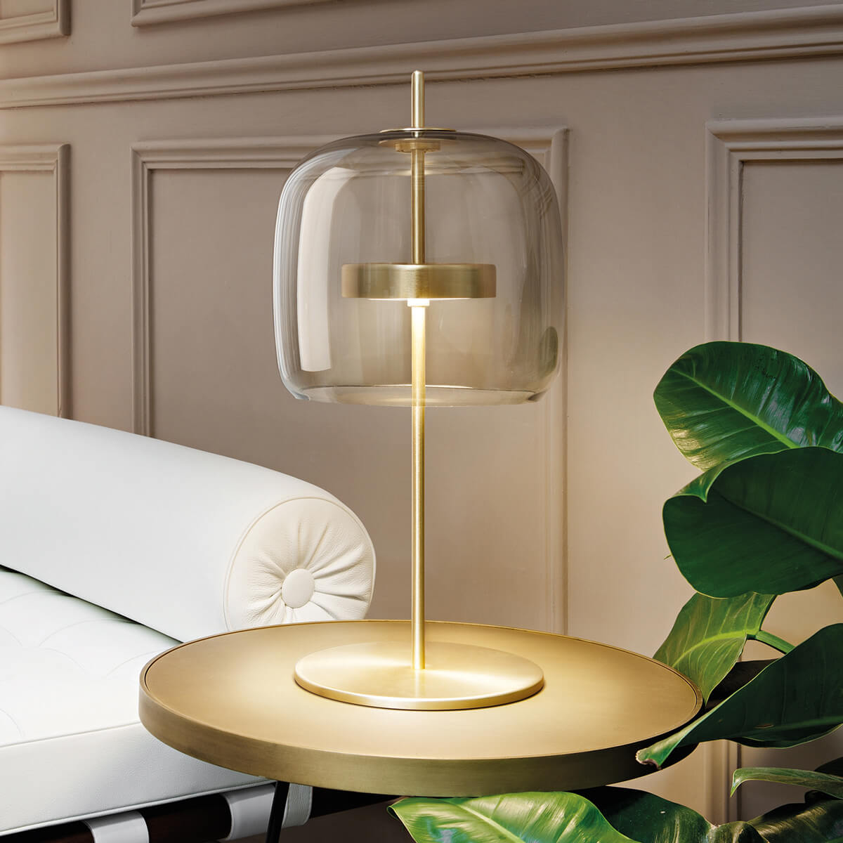 Vistosi Jube table lamp, brushed brass and smoky gray glass, double bell shades on circular brass base with tufted cushion and plant.