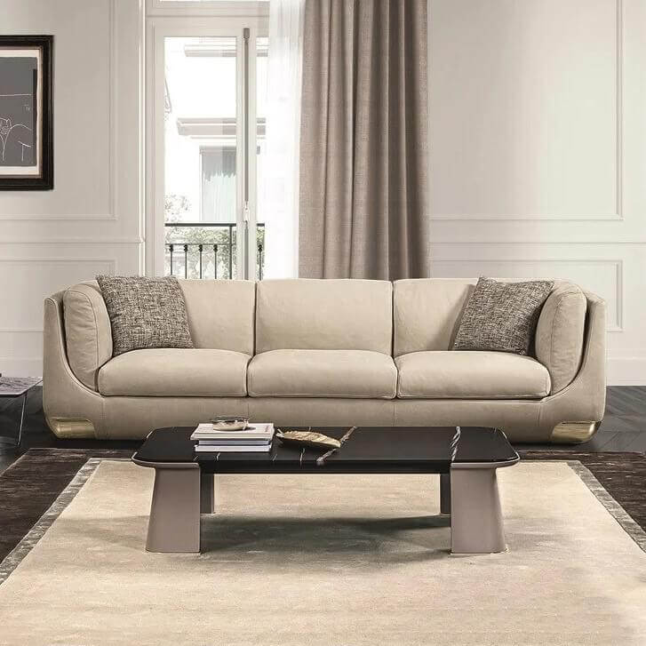 Cushioned three-part form with two rectangular pillows sits before a dark reflective surface and neutral fabric paneling with wall indentations