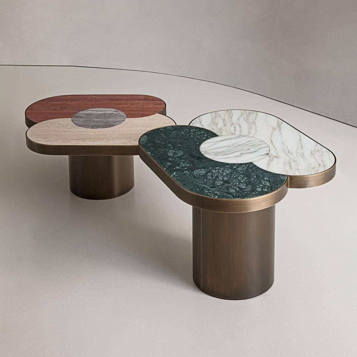 Side tables with brushed bronze bases and multi-toned wood veneer tops, featuring circular marble insets with gray, white, and green veining.