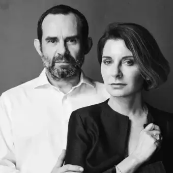 Close-up black and white portrait shows a man and woman facing forward with serious expressions and soft lighting