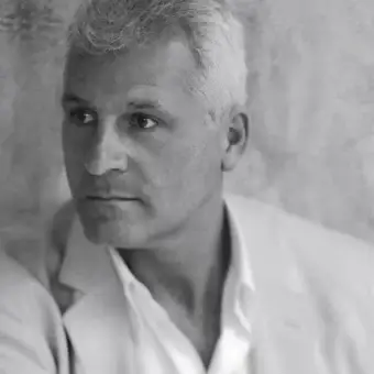 Grayscale portrait of a man facing left with short gray hair, strong features, and an open-collared light shirt