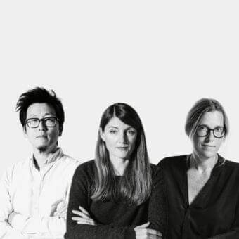 Three people face forward with neutral expressions against a light gray monochromatic background