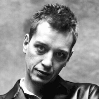 Focused male portrait with short hair and direct gaze against a gray gradient background