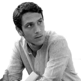 Monochromatic portrait of a young man looking upwards wearing a striped shirt and a ring on his left hand