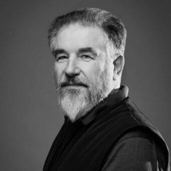 Gray scale portrait of a middle-aged man with short hair and beard looking off frame to the right