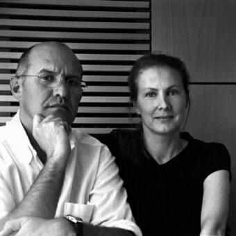 Grayscale image of two people facing each other with a linear background of horizontal elements and diffused lighting