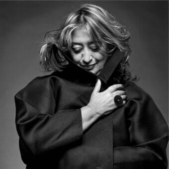Person with layered light hair looks down wearing a dark sleeved garment and a ring with a light stone