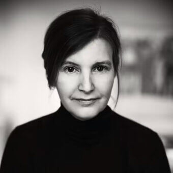 Black and white portrait of Anna von Schewen wearing a black turtleneck, soft blurred background, calm expression, even lighting.